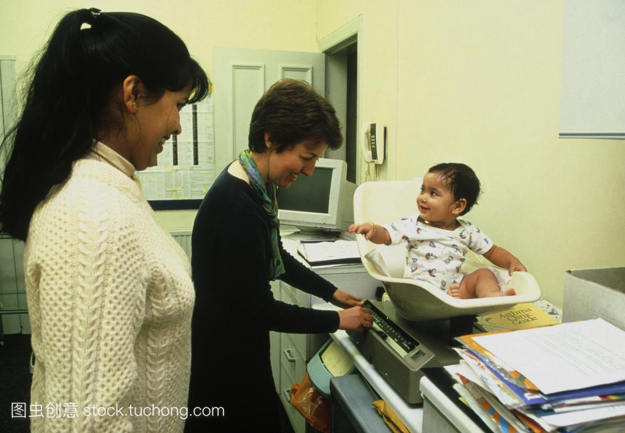 检的健康工作人员测量婴儿在儿科诊所的体重,