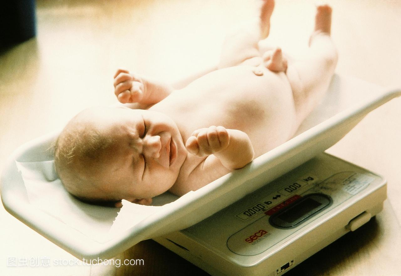 科检查。男婴的重量测量在一次例行产后健康检