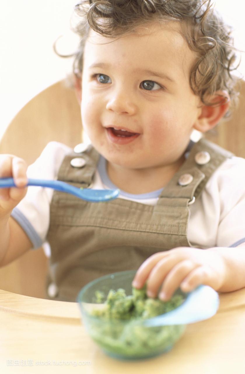 模型发布。小男孩吃。9个月大的小男孩用勺子