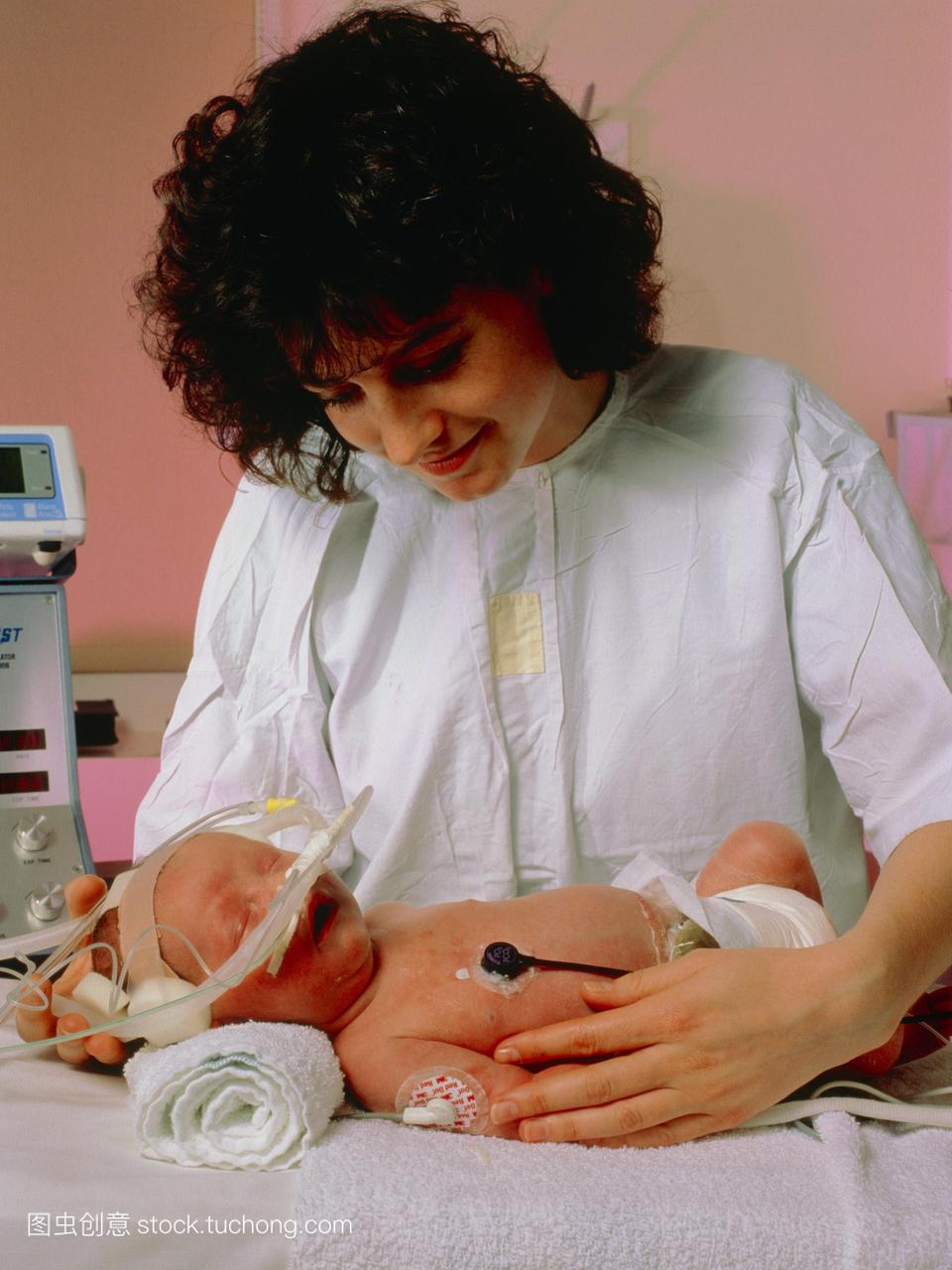 护士在儿科重症监护室里用呼吸器照顾新生儿。