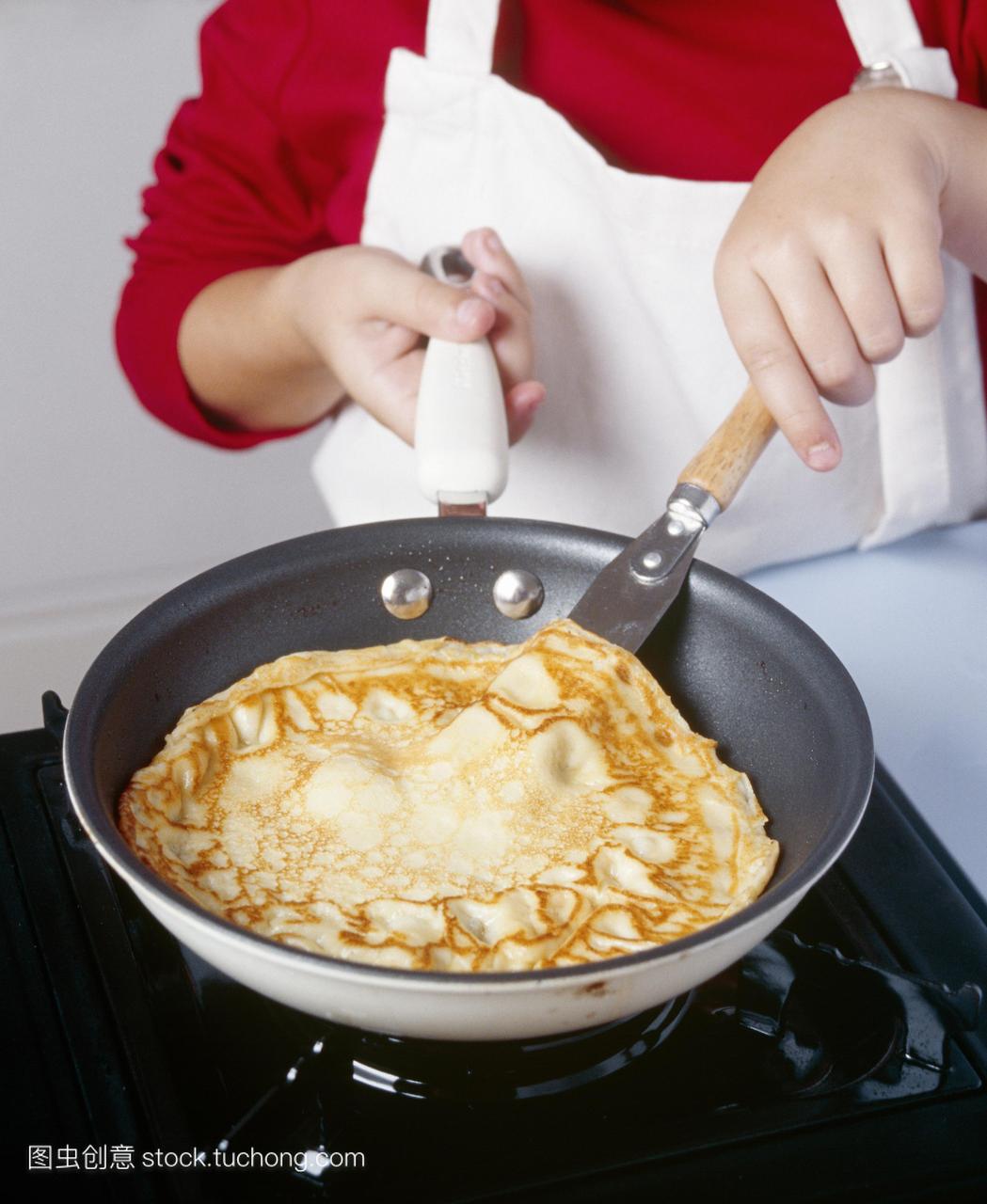 做煎饼。图片3的3。孩子在煎锅里烹饪英语煎