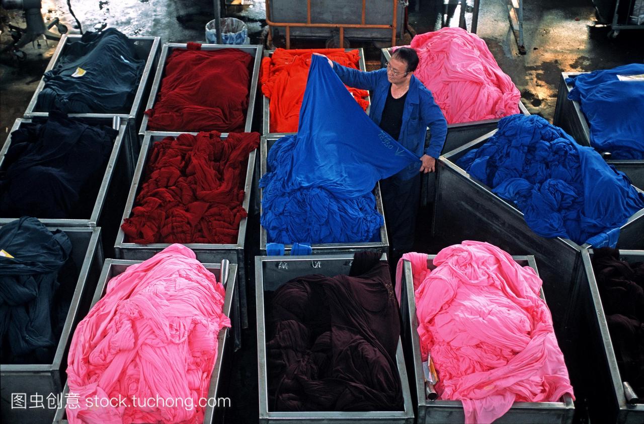 纺织工业。在一家纺织厂检查新染色织物的工人