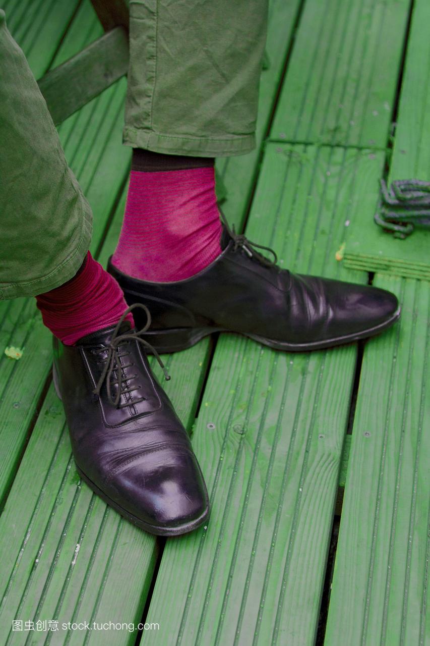 穿粉红袜子,黑皮鞋和绿裤子的男人