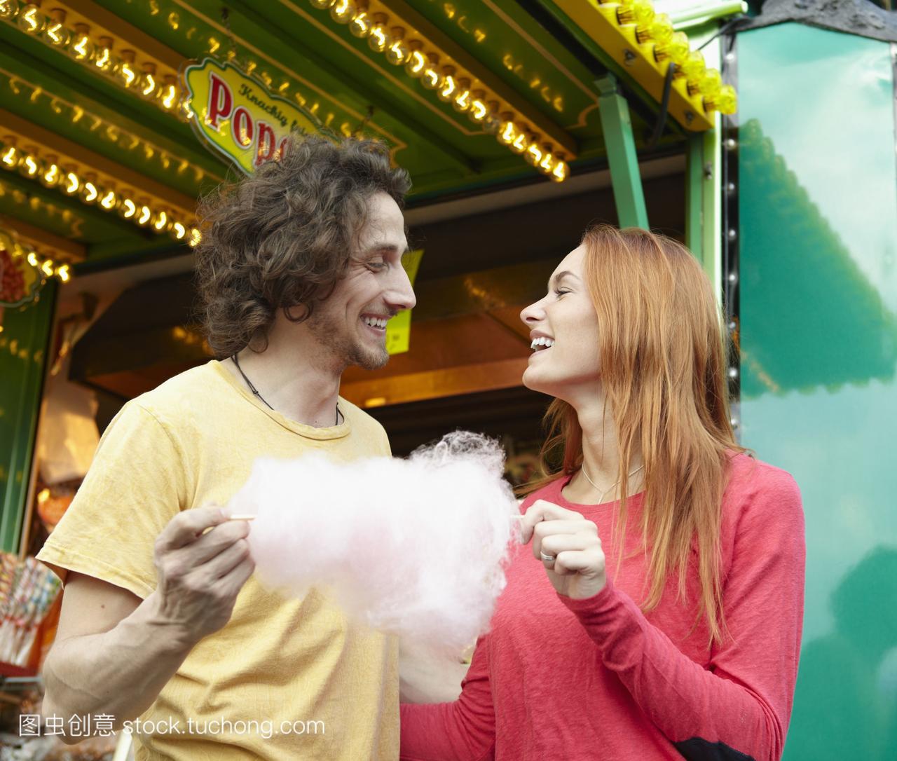 快乐的年轻夫妇在游乐场上吃棉花糖