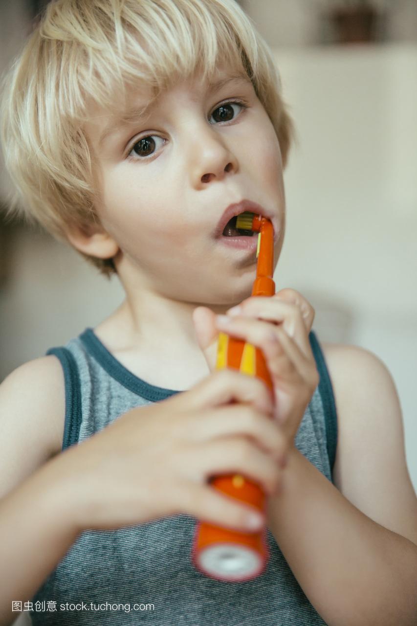 小男孩用电动牙刷刷牙的照片