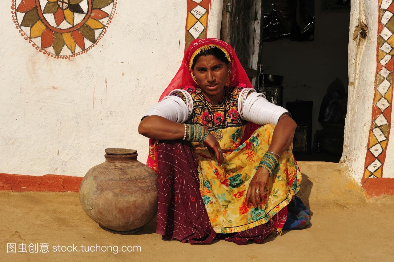 女人水容器坐在一个传统的房子前面塔尔沙漠拉