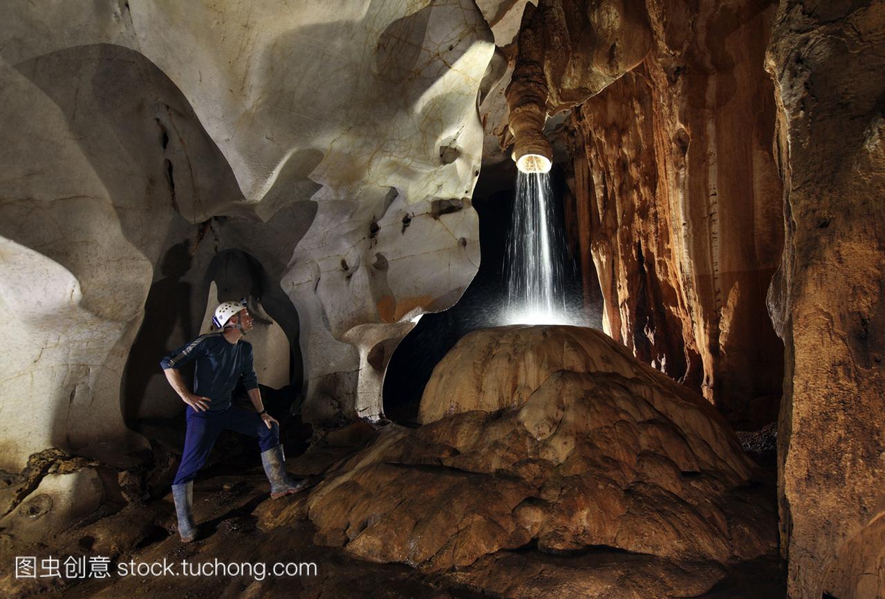 洞瀑布。洞穴探险者在地下深处看着水从洞穴天