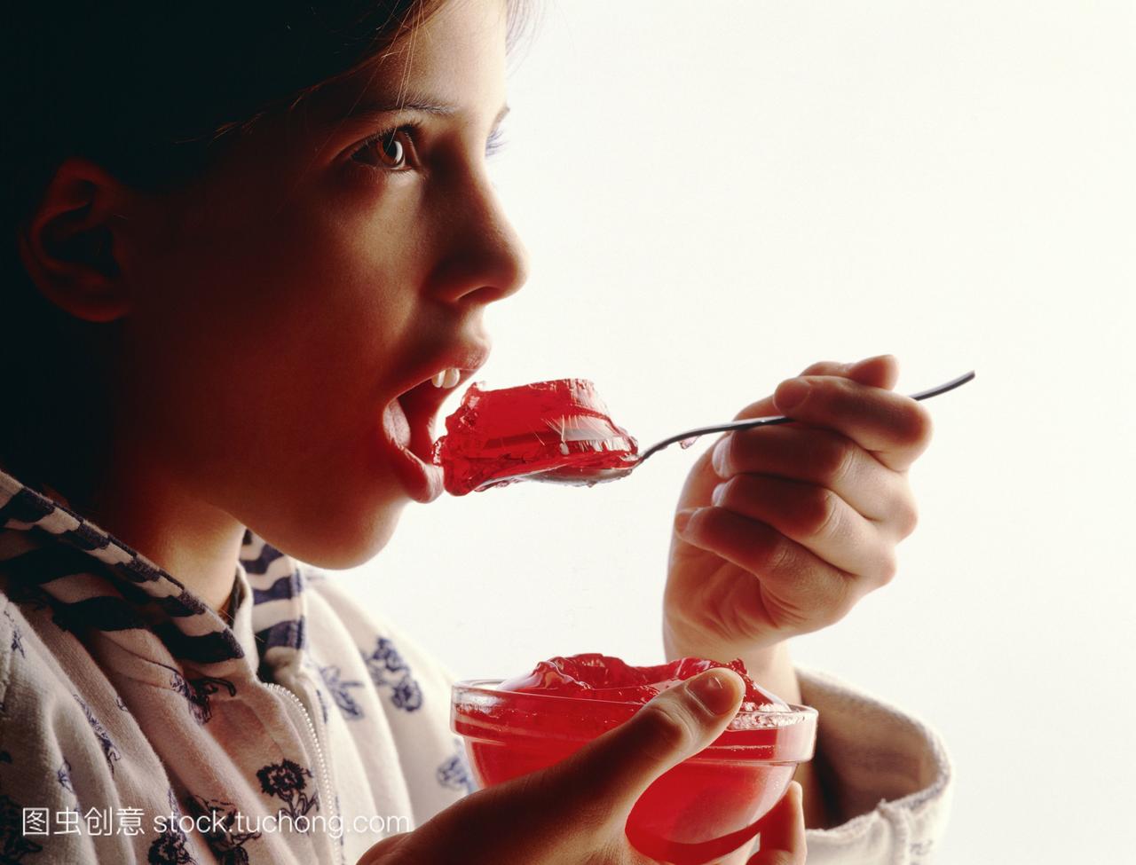 模型发布。儿童营养。小女孩吃一勺红色的果冻