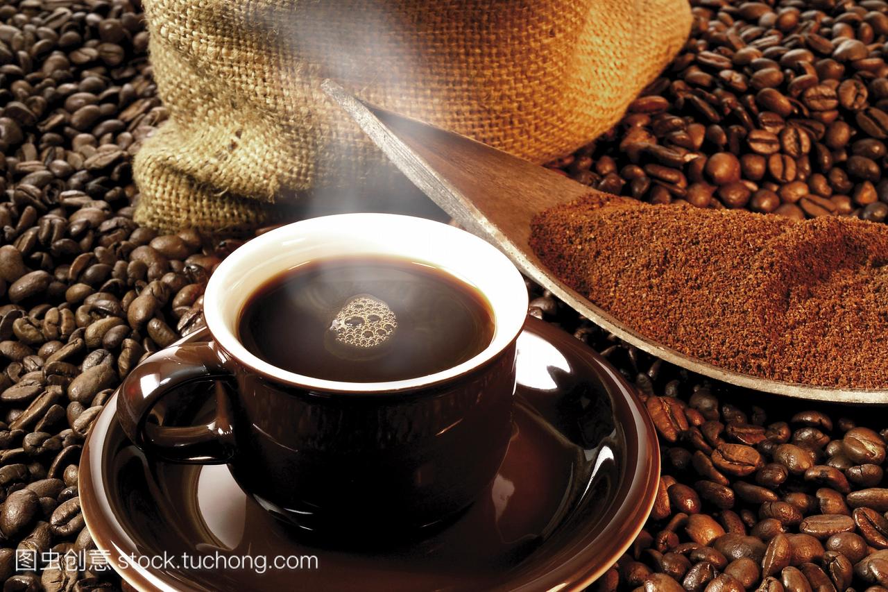 咖啡在一个棕色的杯子里,咖啡豆的床上有磨碎