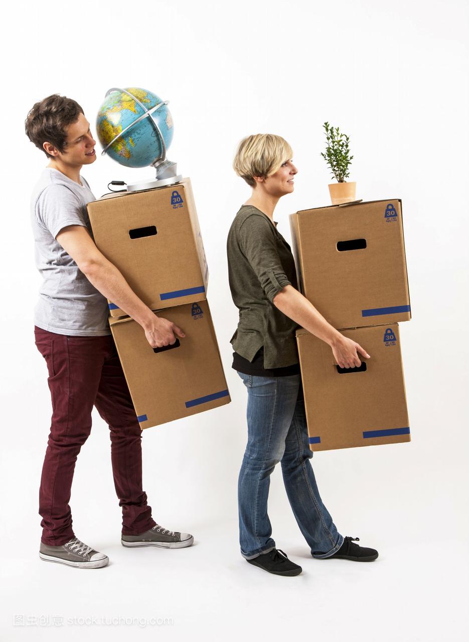 年轻的夫妇搬着移动的箱子,一个地球仪和一个