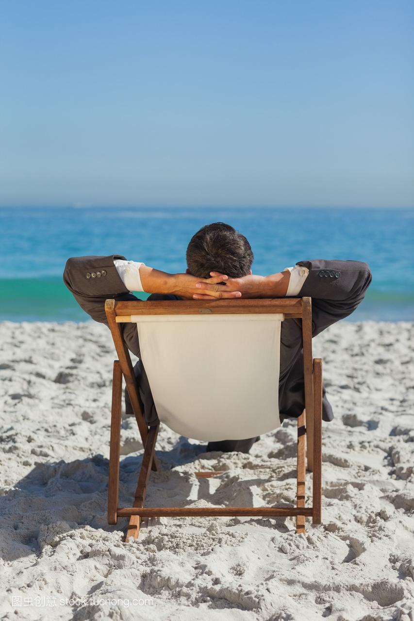 悠闲的年轻商人躺在沙滩上晒太阳