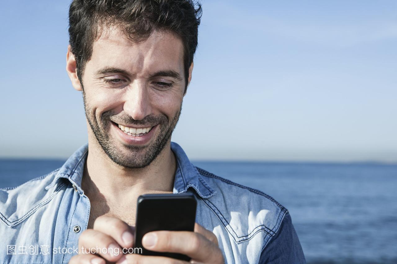 西班牙,中年男子用智能手机微笑