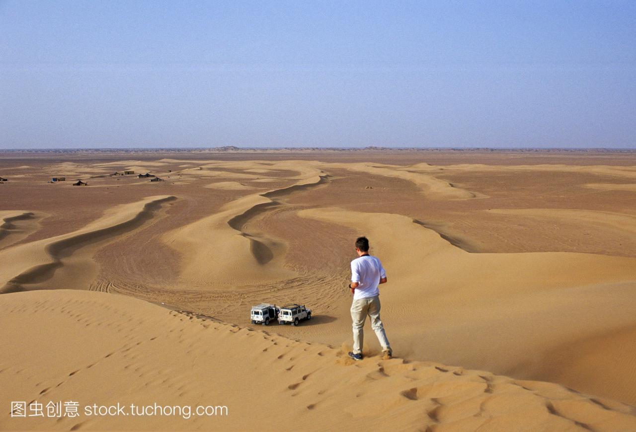 年轻人在摩洛哥撒哈拉沙漠的沙丘上行走