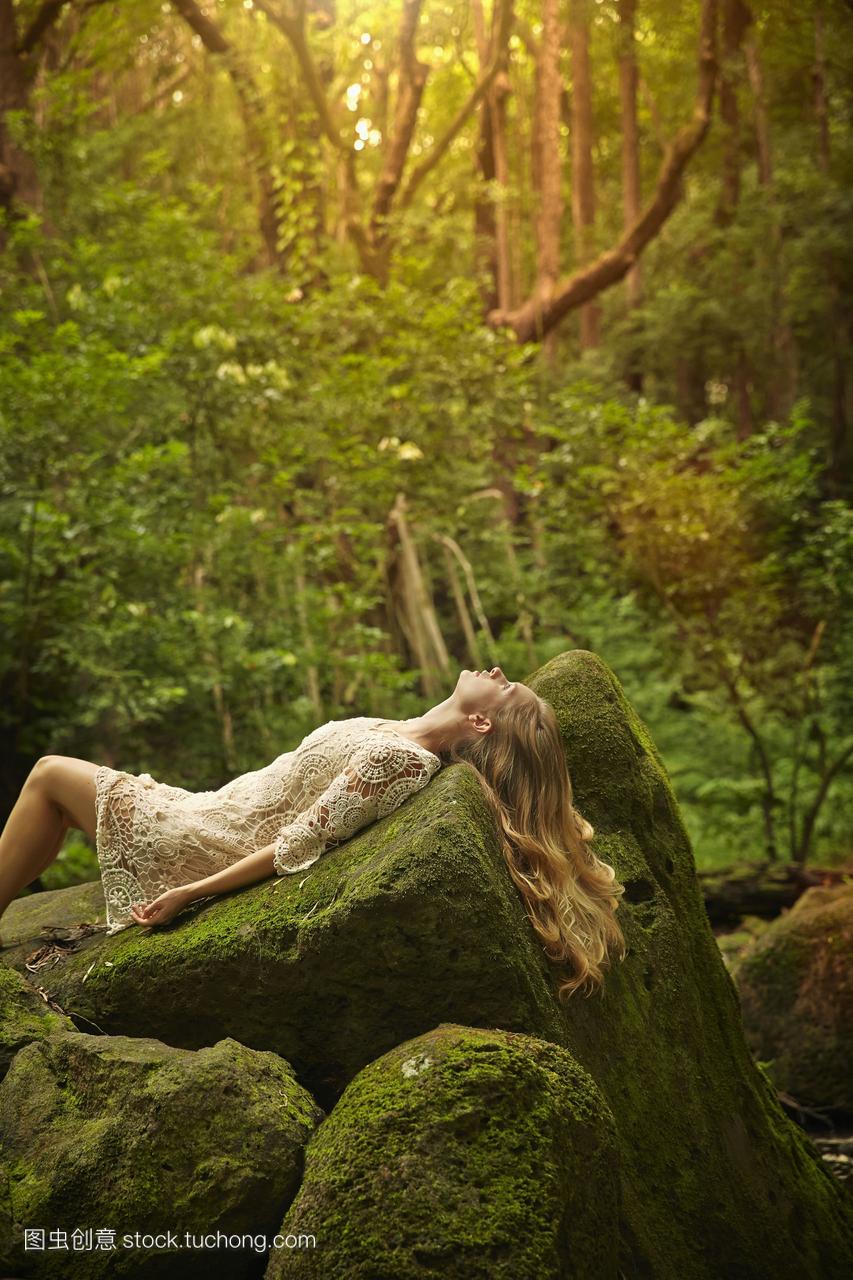 在树林里躺在岩石上的白人妇女