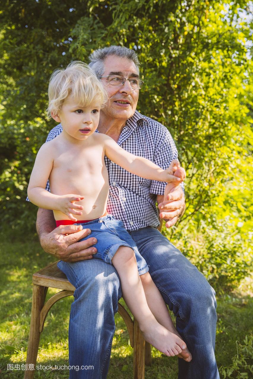 男孩坐在腿上他的爷爷在花园