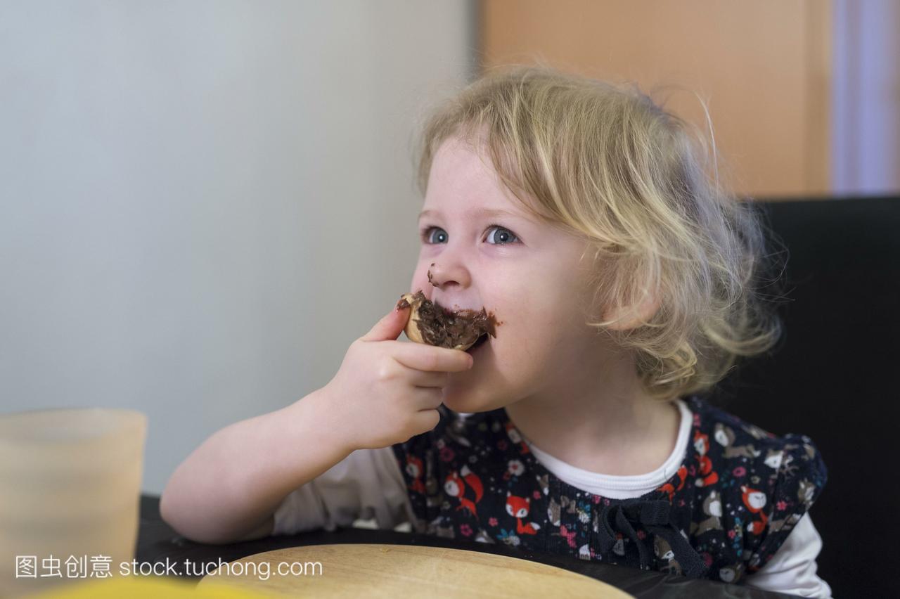 德国,一个金发女孩咬着巧克力面包