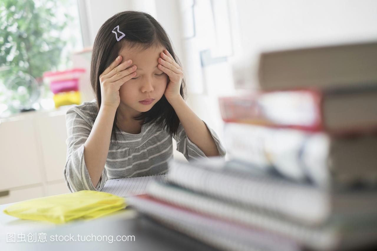 焦虑的中国学生擦着额头做作业