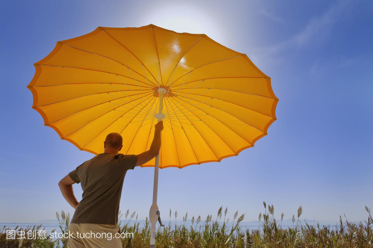 一个人站在橙色的太阳伞下眺望大海;安达卢西
