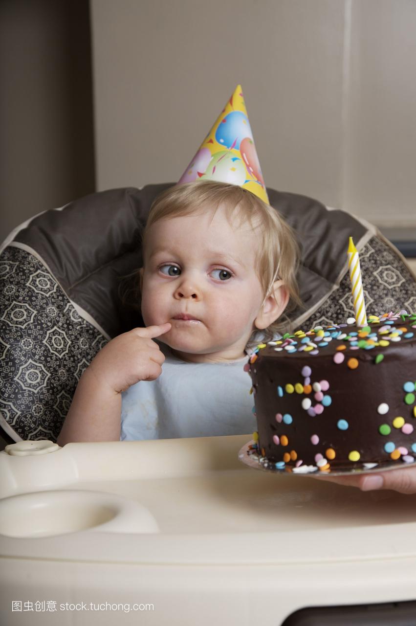 男孩在一岁生日时看着生日蛋糕