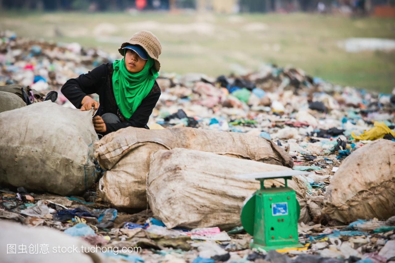 柬埔寨女人用塑料袋子在城市垃圾场;金边